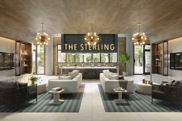 Modern apartment lobby lounge with seating areas and a bar featuring a sign that reads “THE STERLING.”